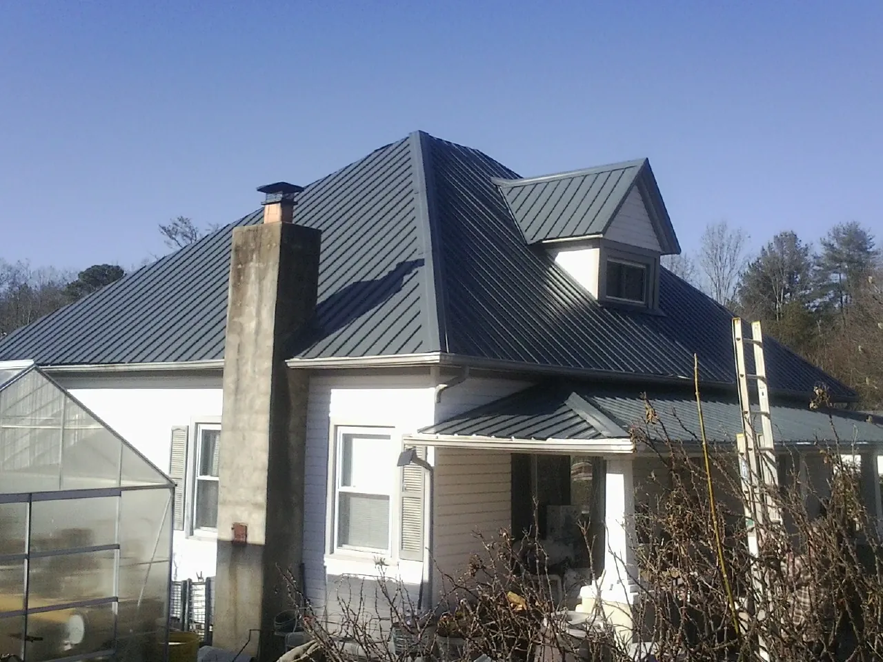Dark blue standing seam metal roof on a white farmhouse with dormer — Slate & Tile Roof Repair by Roofing Brothers in Beaver Falls