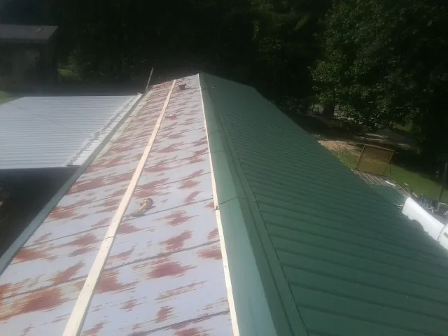 Old rusted panels beside newly installed green metal roofing — Wind Damage Roof Repair by Roofing Brothers in Beaver Falls