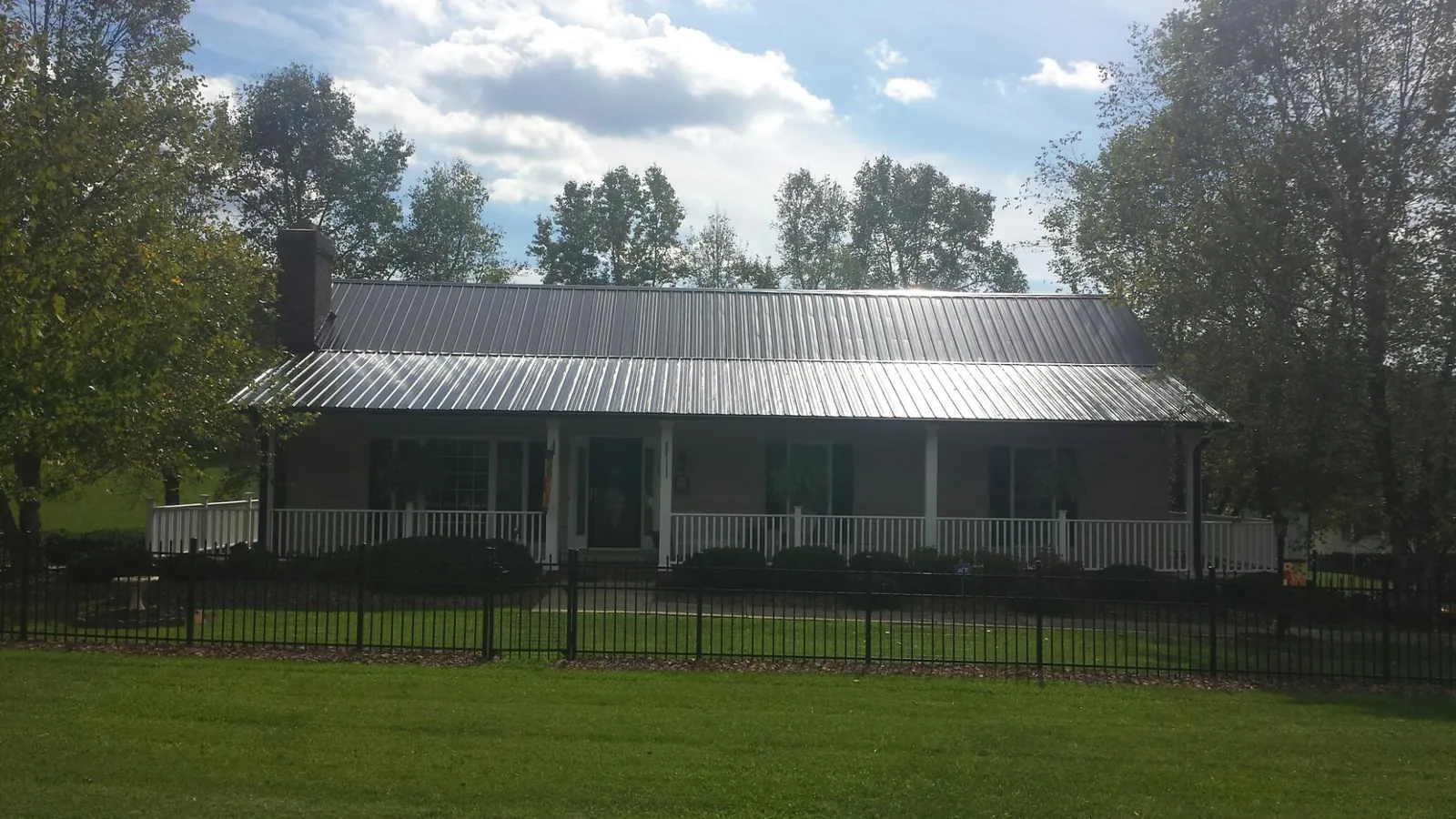 Gray metal roof on a brick ranch with a full width front porch — Gutter Guard Installation work by our crew in Beaver Falls