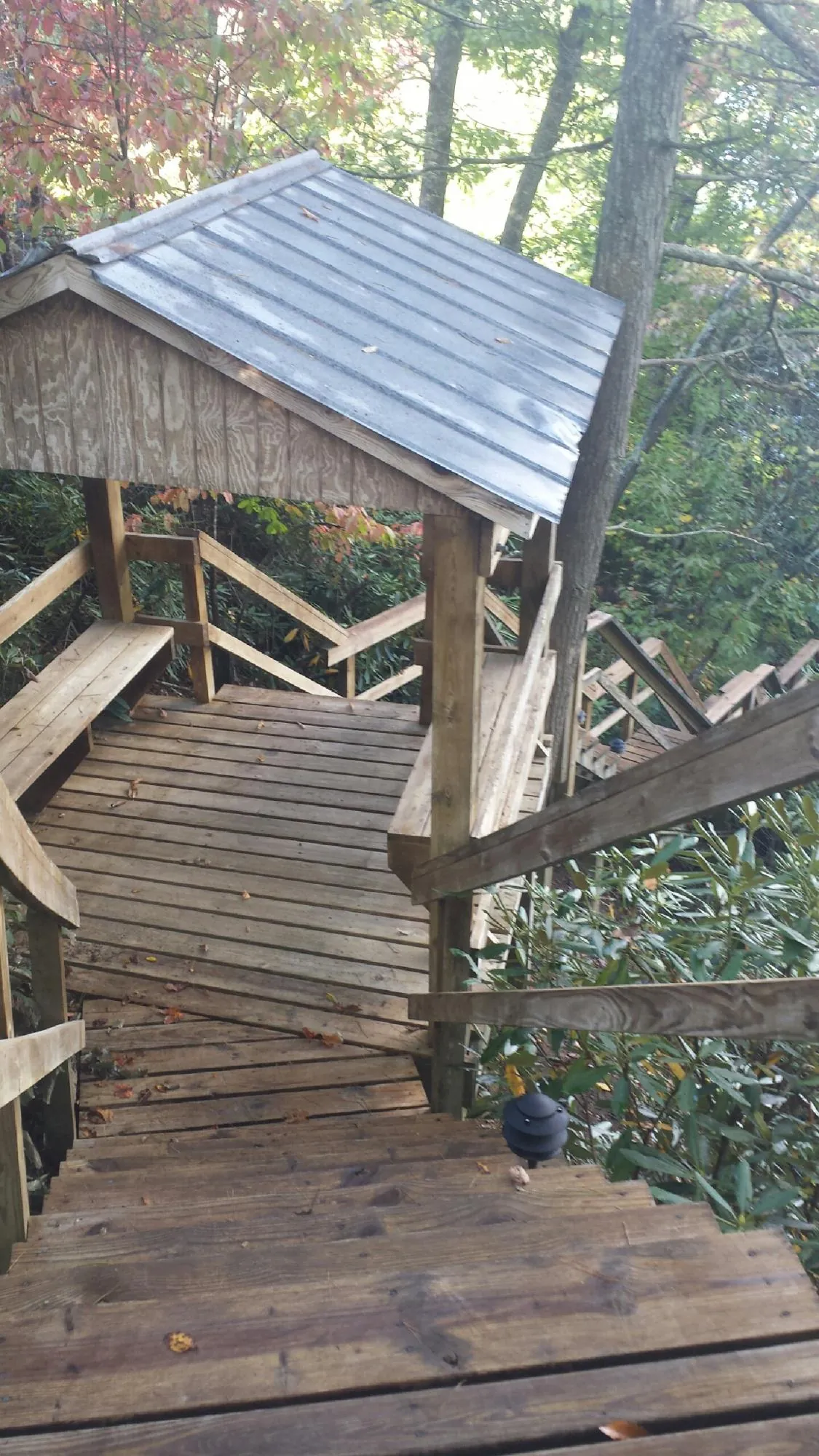 Metal roofed shelter over wooden steps on a wooded walkway — Skylight Repair & Installation work by our crew in Beaver Falls