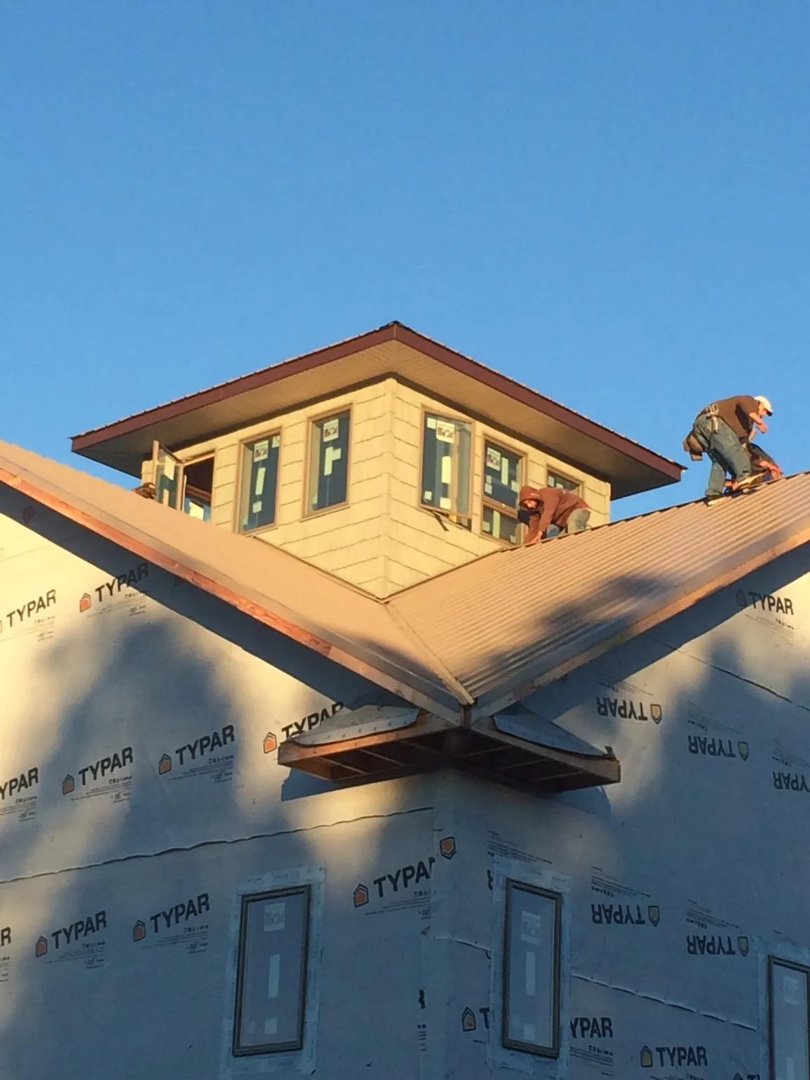 Roofers working around a rooftop cupola on a new metal roof at sunset — Roof Waterproofing in Beaver Falls by Roofing Brothers
